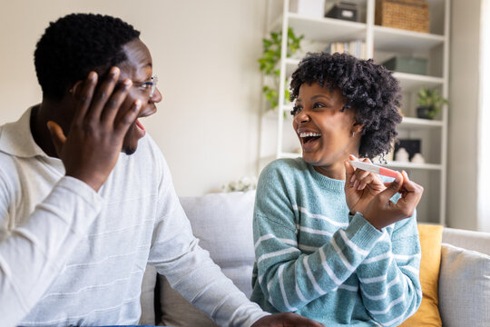 Excited couple celebrating positive pregnancy test result at home - Powered by Adobe