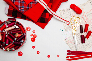 red sewing supplies, fabric with various prints and threads of different shades