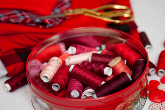 red sewing supplies, fabric with various prints and threads of different shades