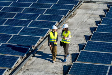 Women engineers walking on solar panel rooftop discussing work