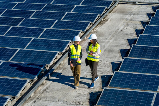 Women engineers walking on solar panel rooftop discussing work