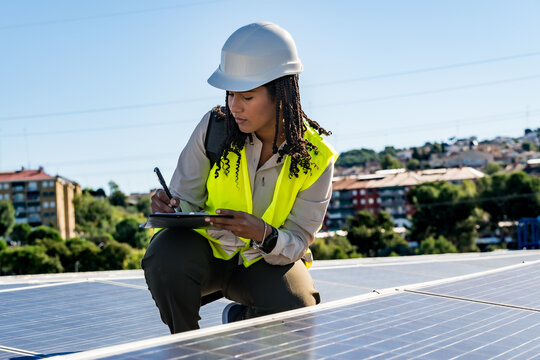 Woman engineer inspecting solar panels on a rooftop - Powered by Adobe