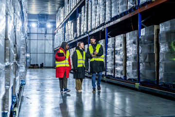 Logistics team discussing inventory in cold storage warehouse