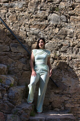 A young, pretty, chubby Latin woman with long dark hair on a stone staircase. The woman is a plus-size model and strikes different poses. Concept beauty and fashion.