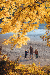 Father holding hands with his two kids during fall walk.