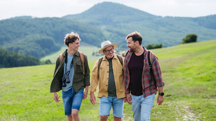 Grandfather, father and teen boy hiking togeter in nature, spending time together during weekend.