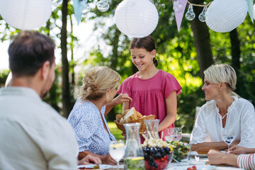 Family sharing food during garden grill party.