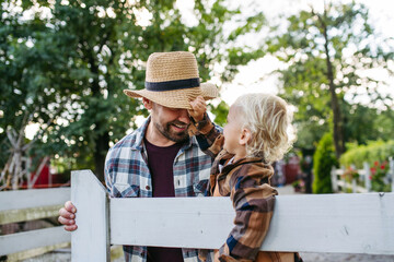 Little boy holding fathers cowboy hat.