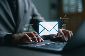 Businessman typing on laptop with email icon overlay, representing digital communication, online marketing, email campaign, and corporate messaging in modern technology workspace.