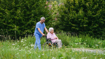 Male home nurse taking care of elderly woman in wheelchair.