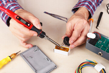 Soldering electrical components of device at service workplace.