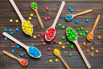 delicious colorful sweet candies on spoon on colored background . Confectionery decor top view with copy space