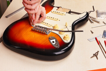 Guitar technician sets pickguard on electric guitar.
