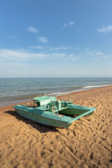 Abandoned catamaran resting on the sandy shore of a vast Issyk-Kul lake in Kyrgyzstan