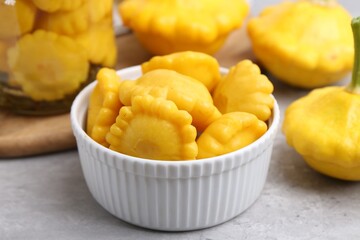 Fresh and pickled pattypan squashes on light grey table, closeup