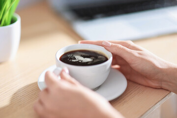 Woman having coffee break at wooden table, closeup