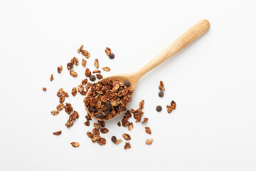 Delicious granola with chocolate chips in spoon on white background, top view