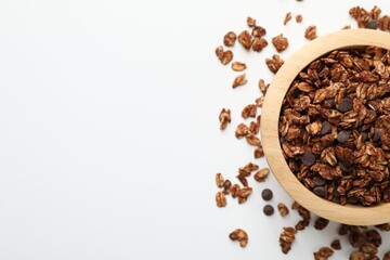 Delicious granola with chocolate chips in bowl on white background, top view. Space for text