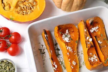 Baked pumpkin and ingredients on white wooden table, flat lay