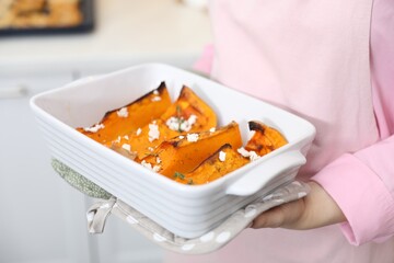 Woman with tasty baked pumpkin indoors, closeup