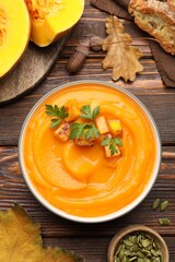 Delicious pumpkin cream soup with parsley served on wooden table, flat lay
