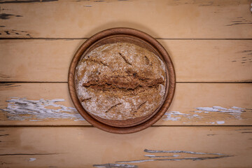 Top view of sourdough walnut bread on round board on aged beige table
