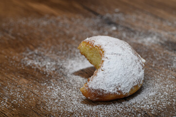 A bitten donut sprinkled with powdered sugar