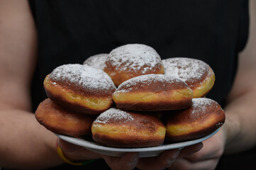 A man holds a plate of handmade homemade parcels sprinkled with powdered sugar.