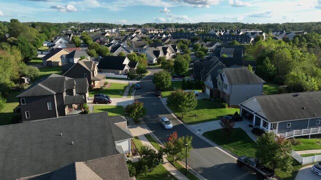 Golden Hour in luxury suburb neighborhood of American town. Drone rising wide shot. Car on street. Colored trees in scenic district of city. Garage and exterior of noble villas. Sunset time.