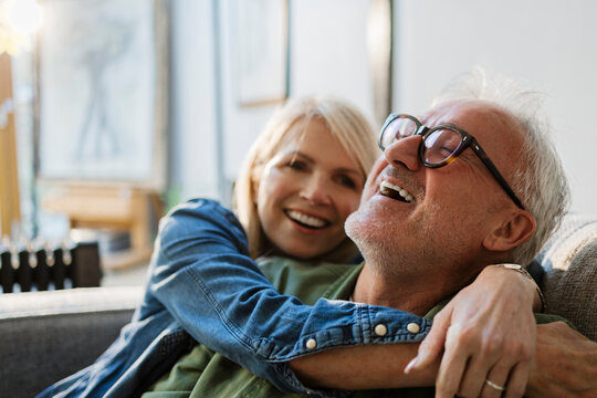 Senior couple embracing and laughing at home - Powered by Adobe