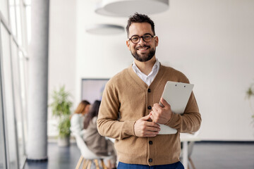 Confident Business Professional in Casual Attire Standing Near Windows in Contemporary Corporate...