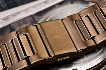 A close-up a bronze stainless steel watch strap. Brushed finish suggests a high-quality watch.