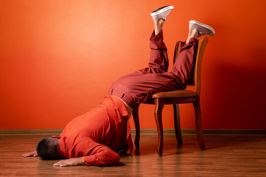 Fatigued man in orange suit suffering burnout falling on chair indoors