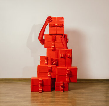 Red gloved hands arranging monochrome red gift boxes in a surreal style