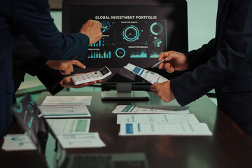 Business professionals closely review a balance sheet and digital Global Investment Portfolio data,...