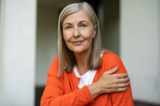 Senior good-looking woman sitting on the steps of her house and feeling contented