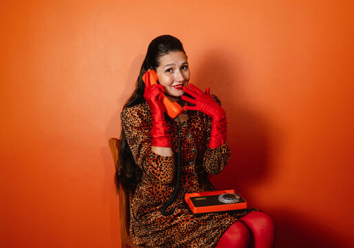 Portrait of woman in leopard print dress holding retro phone with gloves