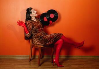 Fashionable woman in leopard print dress holding vinyl records indoors