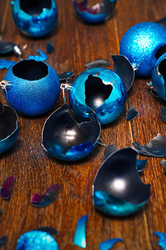Shards of broken blue christmas baubles on wooden floor