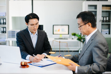 Lawyer consulting client in modern office, reviewing documents with gavel and scales on desk. Ideal for law, finance, consulting, or corporate themes.