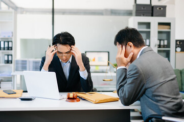 Two businessmen stressed during office meeting, symbolizing financial crisis, debt, or legal problems.