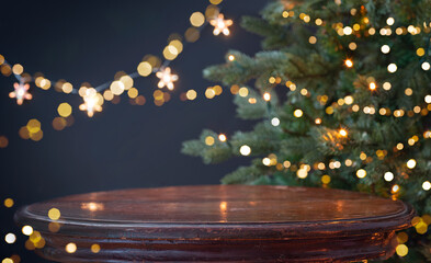 Round wooden table for your product display on blurred Christmas tree decorations dark background
