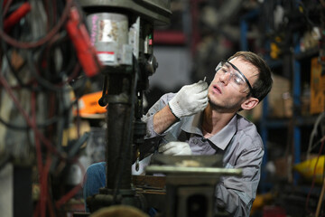 White man technician checking used car damaged engine block at scrap yard warehouse recycle area part. Maintenance engineer inspecting rust oily auto motor old spare part in junkyard for reuse service