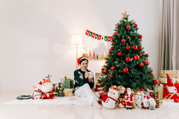 Mother and daughter Christmas Festive living room with a decorated Christmas tree, red ornaments,...