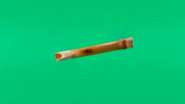 Footage of a traditional bamboo flute rotating in front of a vibrant green screen background