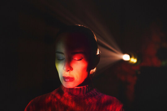 Surreal silhouette with colorful neon projector rays in dark room