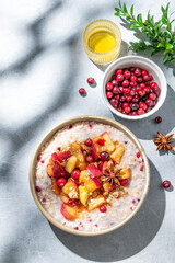 Overnight oatmeal with apple, cranberry, honey and cinnamon in a bowl on a blue background