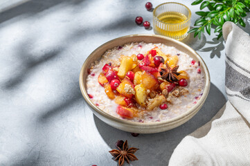 Overnight oatmeal with apple, cranberry, honey and cinnamon in a bowl on a blue background