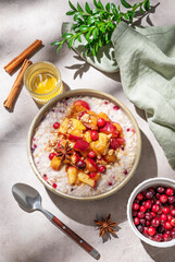 Flat lay of a overnight oatmeal with apple, cranberry, honey and cinnamon in a plate on a light background