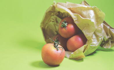 Cherry tomatoes in paper bag and green background.